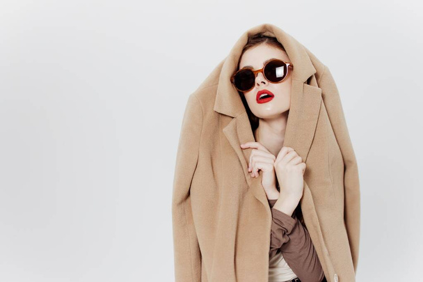 Fotografía de catálogo conceptual. Una chica con gafas y un abrigo en la cabeza posa sobre un fondo blanco. Foto de alta calidad - Foto, imagen