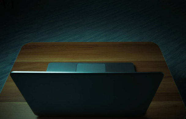 Portátil gris colocado en una mesa de madera en una habitación oscura con luces encendidas. Concepto internet addiction.top ver. - Foto, Imagen