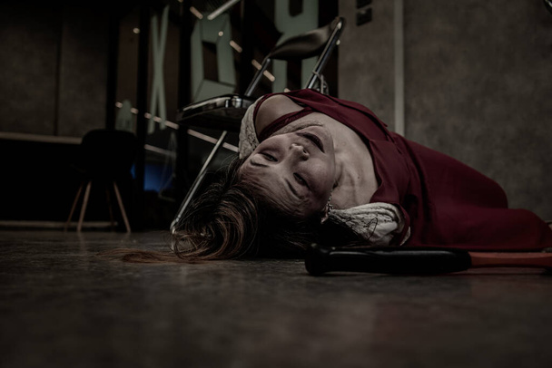 Nahaufnahme: Eine Frau in rotem Kleid wird in einem alten grau-schwarzen Raum zu Tode gefesselt und an einen Stuhl gefesselt. Konzept von Entführung, Prostitution und Geiselnahme. mit Kopierraum. - Foto, Bild