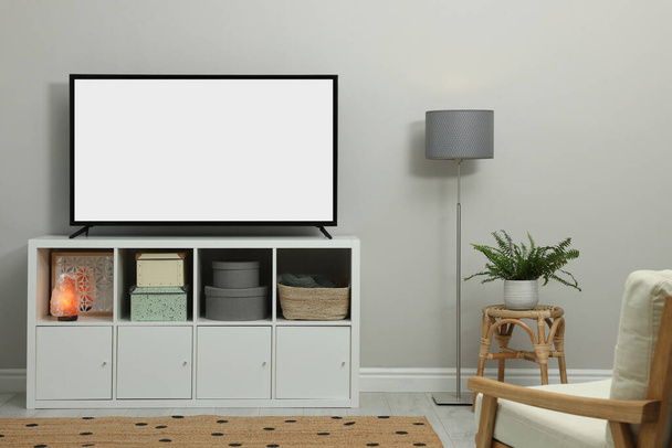 Modern TV on cabinet near light wall indoors. Interior design - Foto, afbeelding