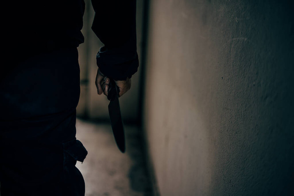 Вид сзади убийцы с ножом в ужасающей темной комнате, который собирается напасть на жертву. - Фото, изображение