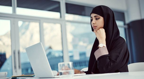 привлекательная молодая арабская бизнесвумен, работающая над своим ноутбуком в офисе. - Фото, изображение