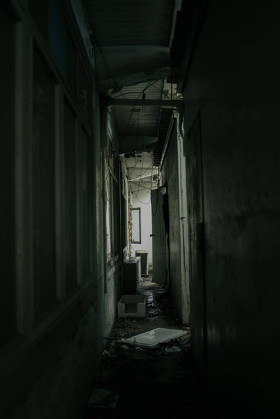 I corridoi all'interno di un terrificante edificio abbandonato sono come in un film horror con foglie al piano.L'interno di una casa abbandonata, strada per l'inferno. Un vecchio edificio abbandonato - Foto, immagini