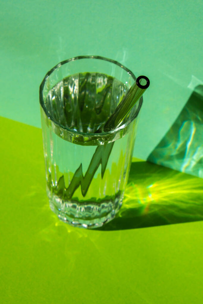 Pajitas de vidrio reutilizables en vidrio con agua sobre fondo verde Set de pajitas ecológicas para beber con cepillo de limpieza. Cero residuos, concepto libre de plástico. Estilo de vida sostenible. Residuos libres de vida Residuos bajos - Foto, imagen