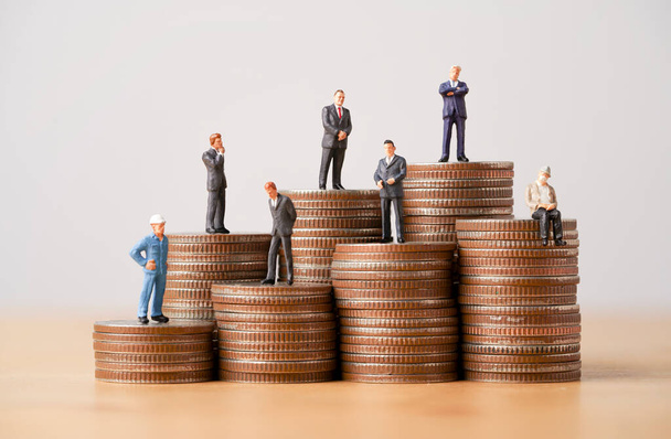 Nombreux chiffre miniature d'entreprise debout sur les pièces empilant pour différents revenus et salaires dans chaque position. - Photo, image