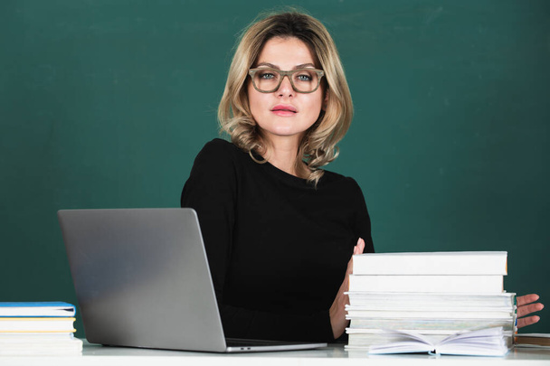 Sensual student woman in eyeglasses near blackboard. Sexy beautiful girl sit on table on chalkboard. Attractive female teacher in college - Photo, image