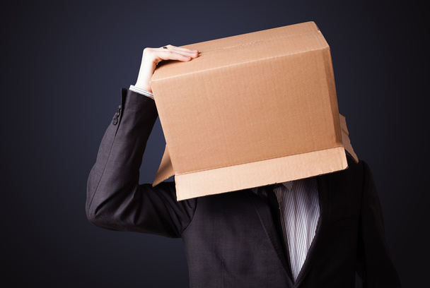 Businessman gesturing with a cardboard box on his head - Fotoğraf, Görsel
