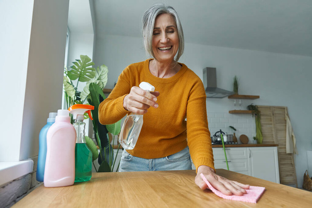 Confident senior woman tidying up the kitchen and smiling - Foto, Bild