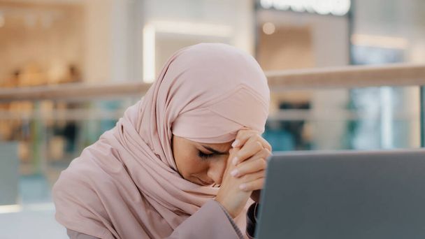 Молодая расстроенная арабская женщина, получающая электронную почту, читает плохие новости на ноутбуке с проблемами со здоровьем, связанными с отказом Банковские уведомления об отказе в предоставлении займа увольнение с работы - Фото, изображение
