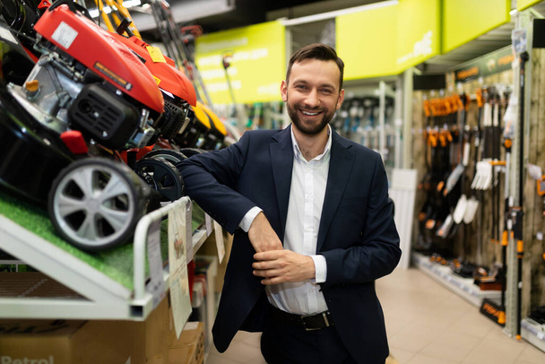 successful entrepreneur owner of a lawn mower shop looking at the camera with a smile. - Photo, Image