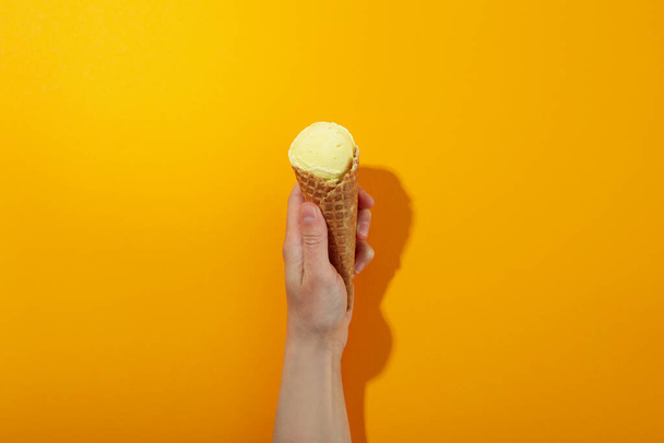 Female hand holds ice cream on orange background - Photo, Image