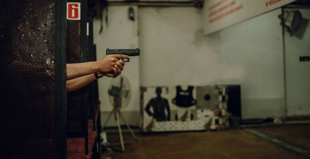 Professionals practice shooting a 9mm pistol inside a shooting range. - Valokuva, kuva