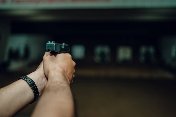 Professionals practice shooting a 9mm pistol inside a shooting range. - Foto, Imagen