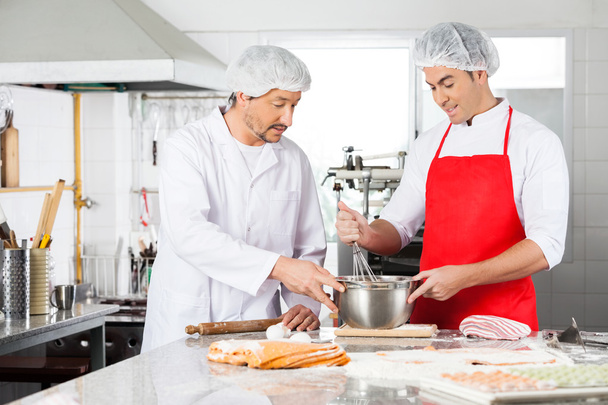 Chefs Discussing While Preparing Ravioli Pasta In Kitchen - Foto, Bild
