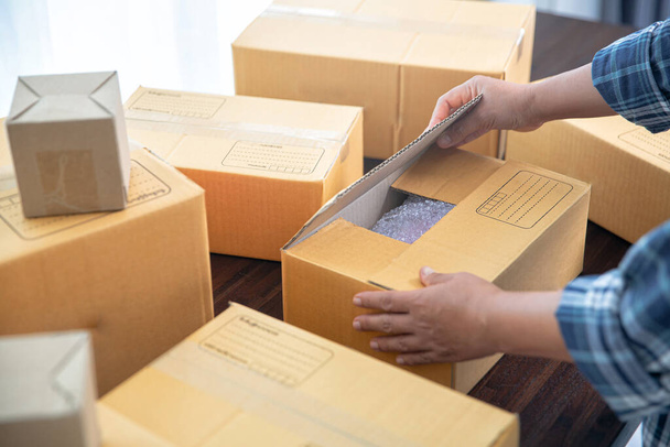 Closeup view of female online store small business owner seller entrepreneur packing package post shipping box preparing delivery parcel. - Photo, Image