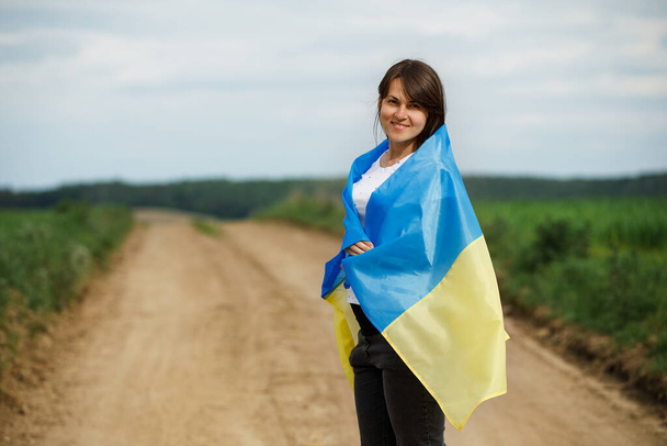 Femme avec le drapeau ukrainien dans le champ de blé. Joyeux garçon célébrant le jour de l'indépendance. - Photo, image