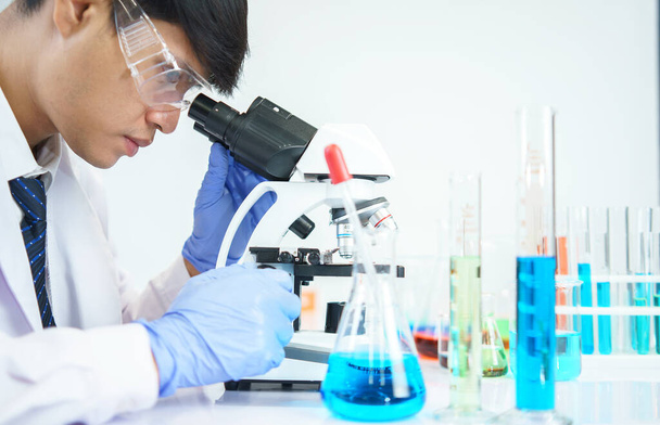 Aziatische wetenschappers bestuderen serieus de chemische samenstelling in het laboratorium. Gespecialiseerd in Young Biotechnology Gebruik geavanceerde microscoop apparatuur. - Foto, afbeelding