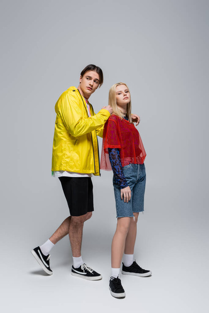 Full length of stylish young couple standing on grey background - Foto, Imagem