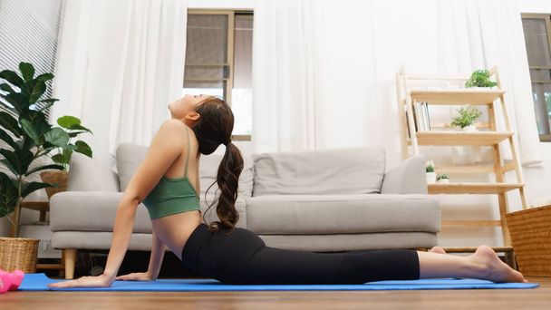 Yoga e conceito de bem-estar, Jovem mulher asiática fazendo ioga para mentir em cobra posar no tapete em casa. - Foto, Imagem