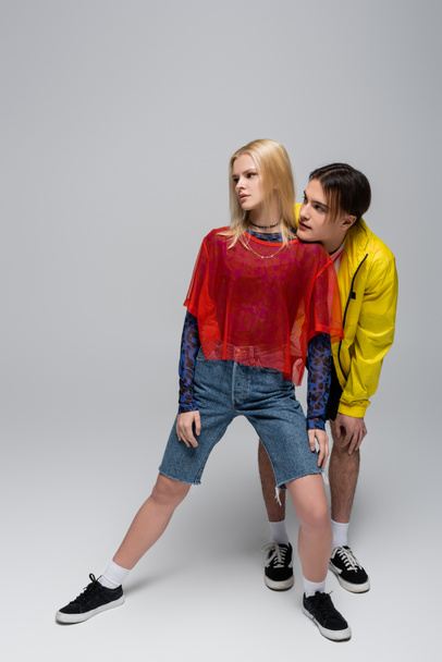Young trendy couple looking away on grey background - Foto, Imagem