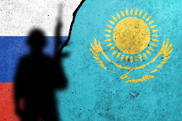 Russia and Kazakhstan flags painted on a concrete wall with soldier shadow. Relationship between Kazakhstan  and Russia - Fotó, kép