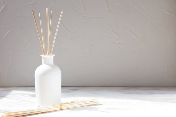 Parfüms für zu Hause. Aromatischer Schilfrohrdiffusor mit einem Strauß Stäbchen auf weißem Hintergrund. Das Konzept von Ruhe, Entspannung und Genuss - Foto, Bild