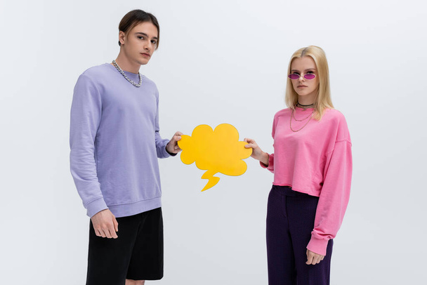 Stylish young couple holding thought bubble isolated on grey  - 写真・画像