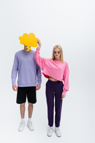 Stylish model in sunglasses holding thought bubble near boyfriend on grey background - Photo, Image