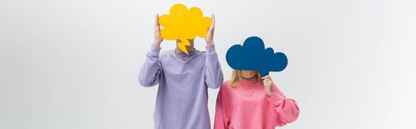 Young couple holding thought bubbles near faces isolated on grey, banner  - Foto, imagen