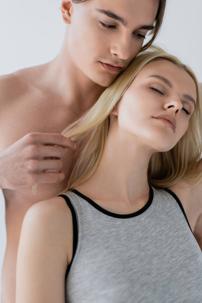 Shirtless man touching hair of blonde girlfriend isolated on grey  - Foto, immagini