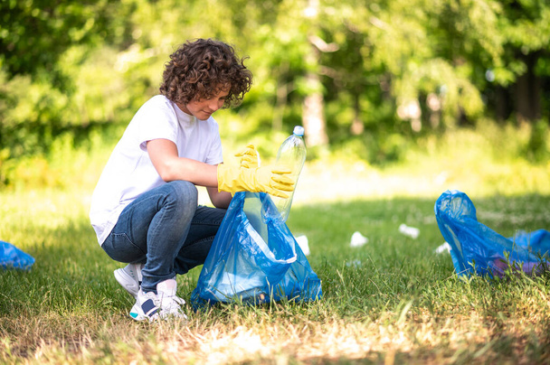 Zero waste. Young guy collecting and sorting garbage in the park - 写真・画像