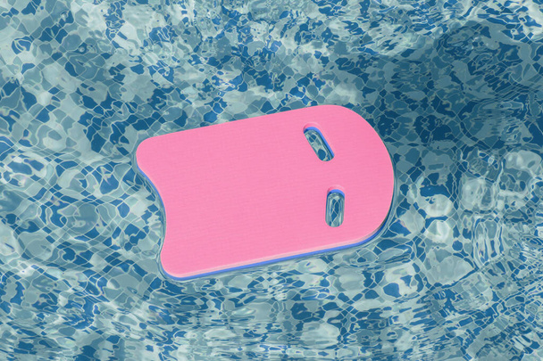 Safe pool training aid float foam board tool. Pink Swimming kickboard on blue water surface of swim pool. Mockup, copy space for text or design. Water sport, active lifestyle - Photo, Image
