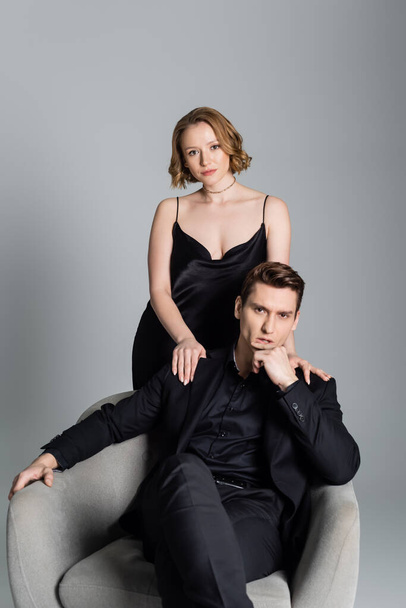 sexy couple in black clothes looking at camera isolated on grey - Foto, Imagen