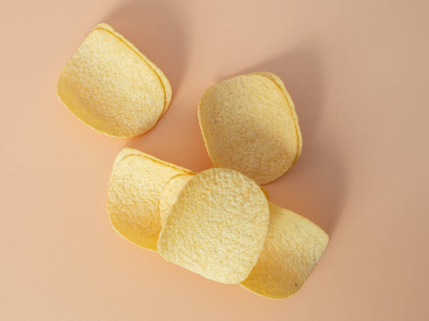 Crisps. Crispy potatoes. Potato chips on an orange background. Close-up. - Zdjęcie, obraz