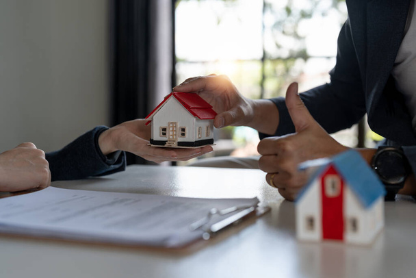 Real estate company to buy houses and land are delivering keys and houses to customers after agreeing to make a home purchase agreement and make a loan agreement. Discussion with a real estate agent. - Photo, image