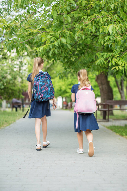 Twee gelukkige kinderen gaan naar school met rugzakken. Concept terug naar school, leren, vriendschap en jeugd. - Foto, afbeelding