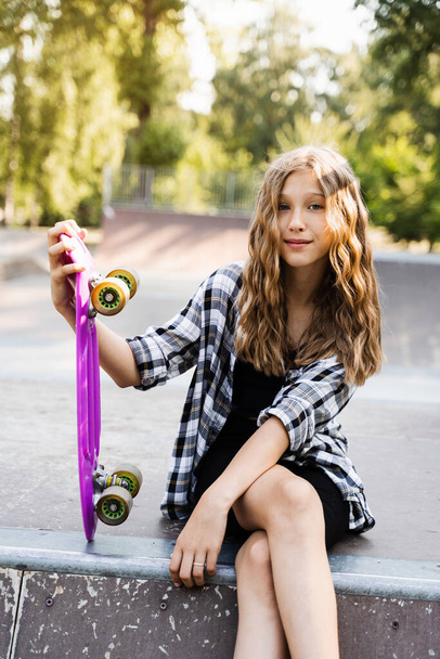 Extreme child girl with penny board in her hands on skate playground. Sports Lifestyle. Active teenager posing on sports ramp - Foto, imagen