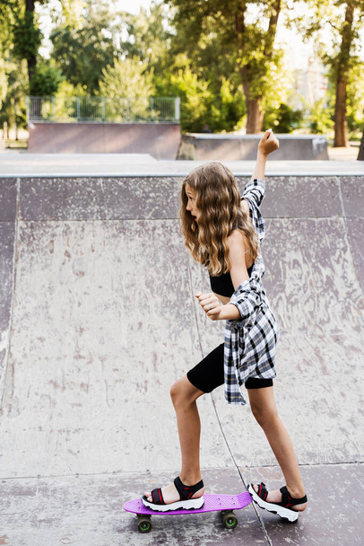 Kind meisje rijdt op een penny board of skate board. Sportuitrusting voor kinderen. Tiener met penny board op skate park speeltuin - Foto, afbeelding