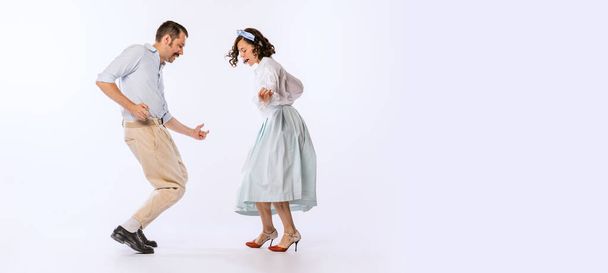 Portrait of young beautiful couple, man and woman, dancing retro dance isolated on white background. Cheerful people. Concept of vintage fashion, hobby, activity, art, music, party, creativity and ad - Fotografie, Obrázek