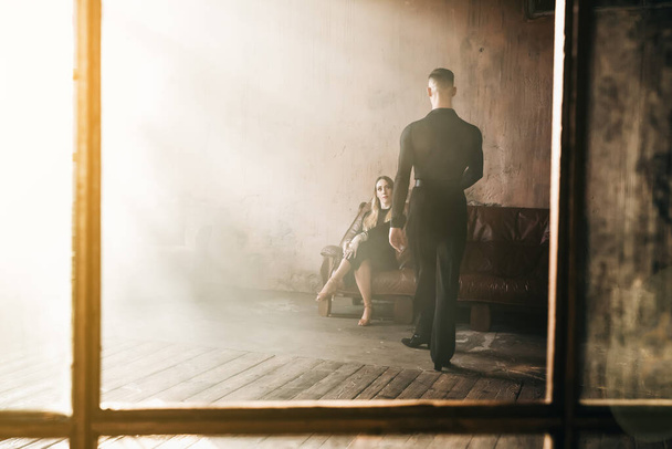 Couple of two professional ballroom dancers is dancing on loft studio. Beautiful art performance with heavy smoke. Sport life concept. Passion and emotional dance. - Photo, Image
