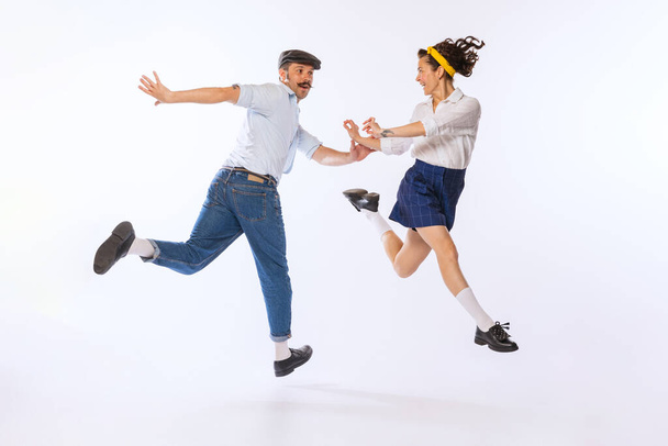 Portrait of young beautiful couple, man and woman, dancing retro dance isolated over white background. Cheerful hobby. Concept of vintage fashion, hobby, activity, art, music, party, creativity and ad - Foto, Imagen