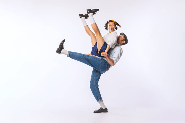 Portrait of young beautiful couple, man and woman, dancing isolated over white studio background. Dance lift element. Concept of vintage fashion, hobby, activity, art, music, party, creativity and ad - Foto, imagen