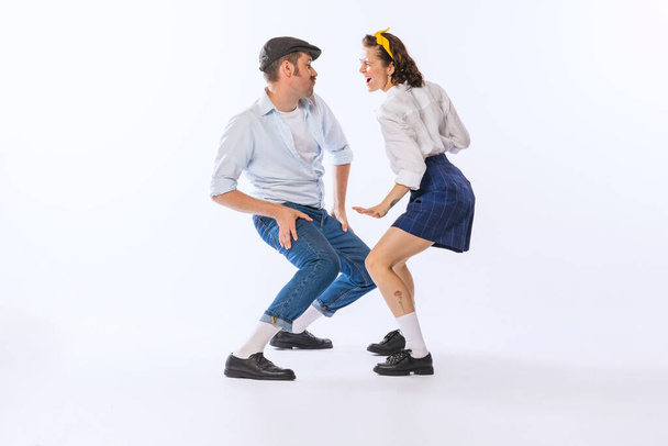 Portrait of young emotive couple, man and woman, dancing retro dance isolated over white background. Funny faces. Concept of vintage fashion, hobby, activity, art, music, party, creativity and ad - Foto, afbeelding