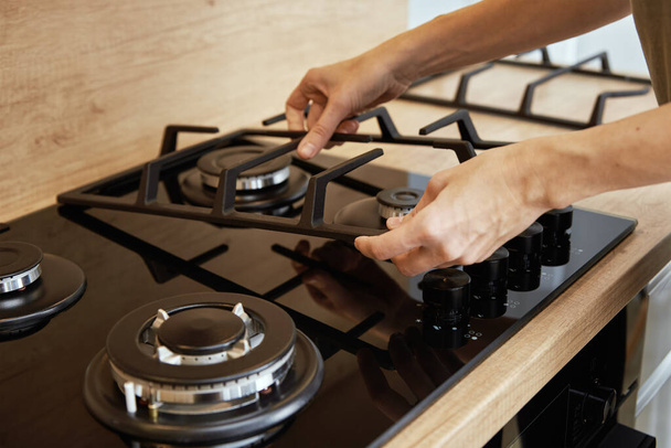 Hands installing gas stove grill after cleaning, Kitchen appliance maintenance - Fotó, kép