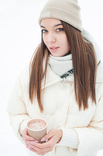 Lächelnde junge Frau beim Kaffeetrinken im verschneiten Wald. Winterurlaub. - Foto, Bild