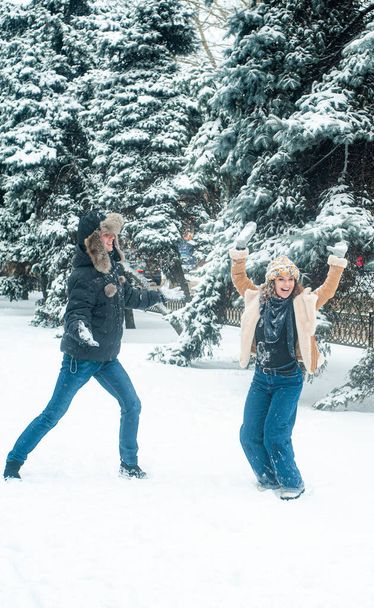 Счастливая пара веселится со снегом. Женщина и мужчина ходят по зимнему лесу.  - Фото, изображение