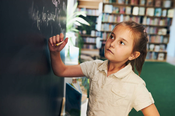 Little girl writing on blackboard. Smart student put solve on chalkboard. Back to school. Child having class. Schoolgirl learning at primary school. Elementary education - Fotó, kép