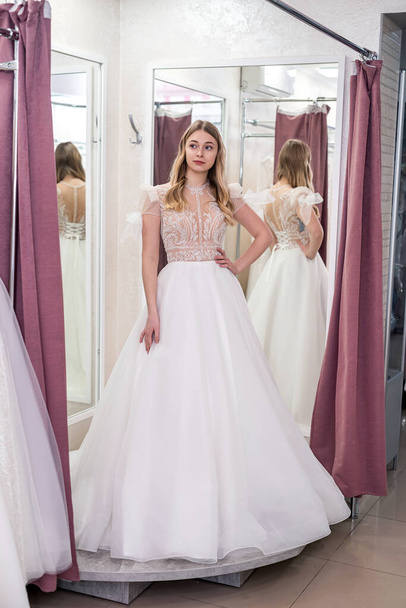 young prety woman is trying white wedding dresses in shop - Foto, Bild