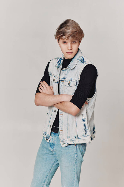 young handsome guy with modern haircut in denim on gray background. - Valokuva, kuva