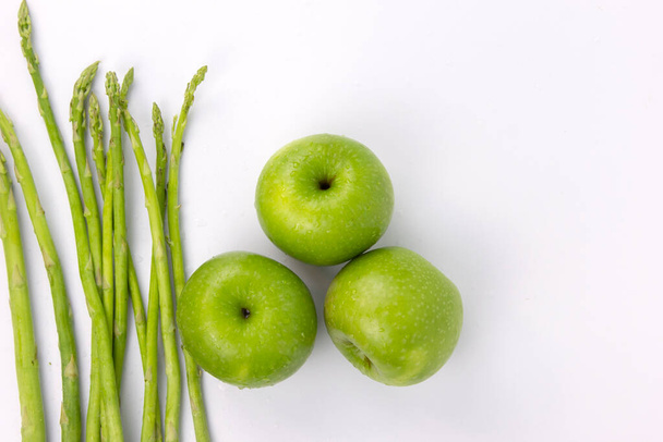 Зеленый спаржа и свежие яблоки изолированы на белом фоне, здоровые концепции питания - Фото, изображение